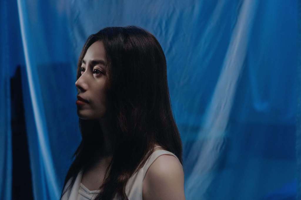 〈小事情〉MV中徐懷鈺身穿米白色洋裝,眼神溫柔而深情。(圖/滾石唱片提供)