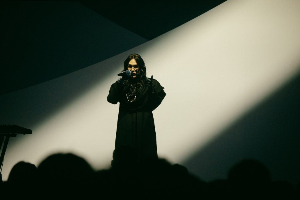 穿搭品味風格獨具的鶴 The Crane,身著一席黑色寬肩外套與拼接長裙登場